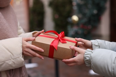 Photo of Friends with Christmas gift on city street, closeup