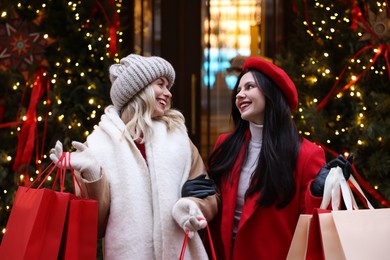 Photo of Happy friends with paper bags on city street. Christmas season