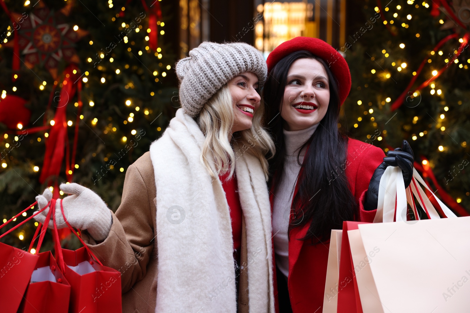 Photo of Happy friends with paper bags on city street. Christmas season