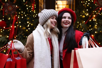 Photo of Happy friends with paper bags on city street. Christmas season