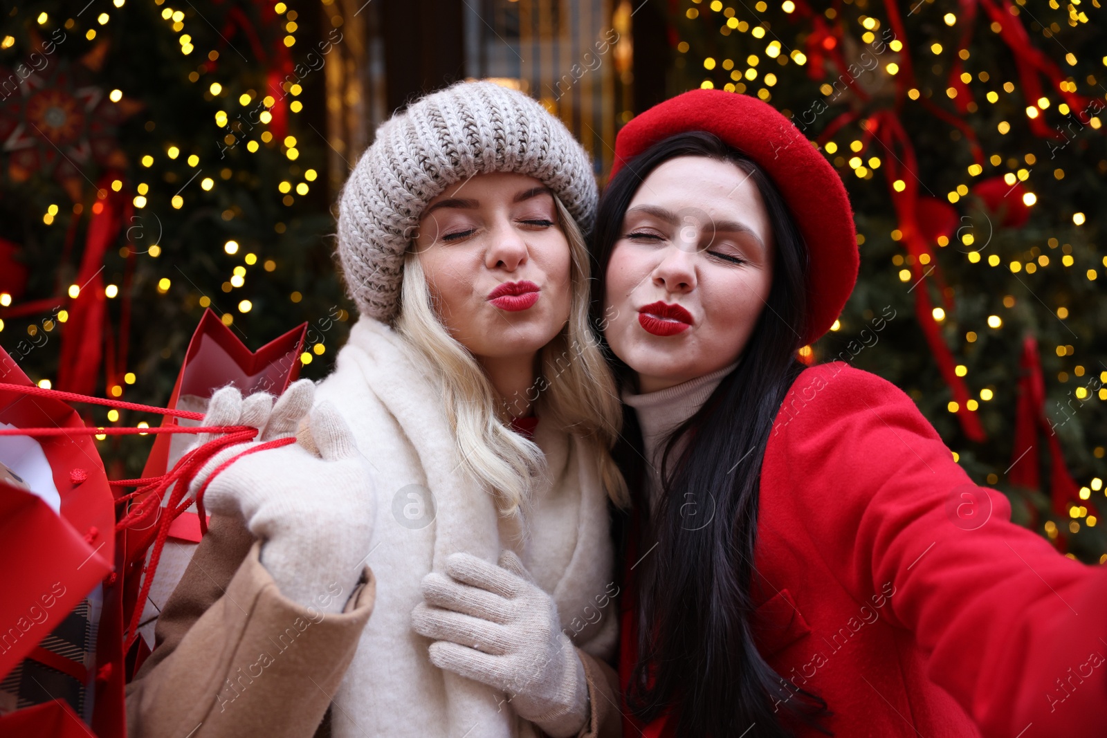 Photo of Friends with shopping bags taking selfie on city street. Christmas season