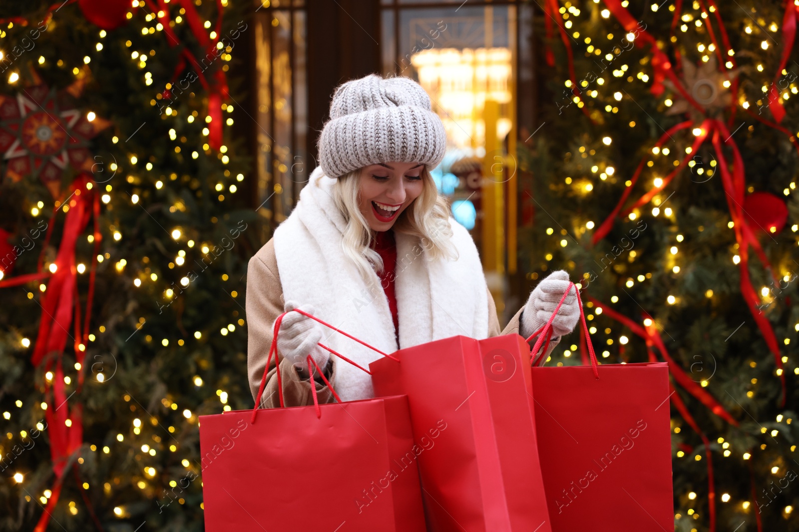 Photo of Happy woman with shopping bags on city street. Christmas season