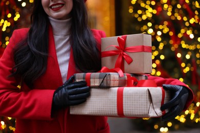 Photo of Woman with Christmas gifts on city street, closeup