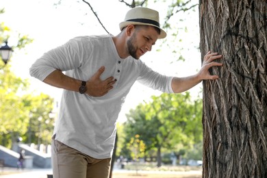 Photo of Man having heart attack near tree in park