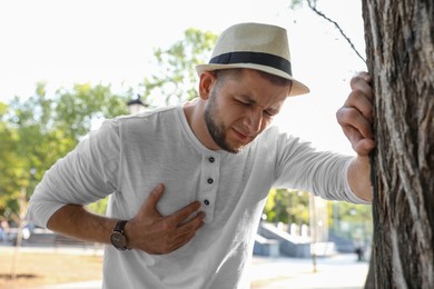 Photo of Man having heart attack near tree in park