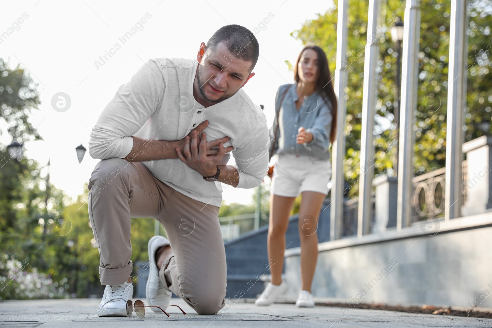 Photo of Man having heart attack near worried woman on city street