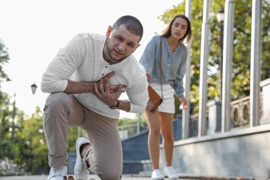 Photo of Man having heart attack near worried woman on city street