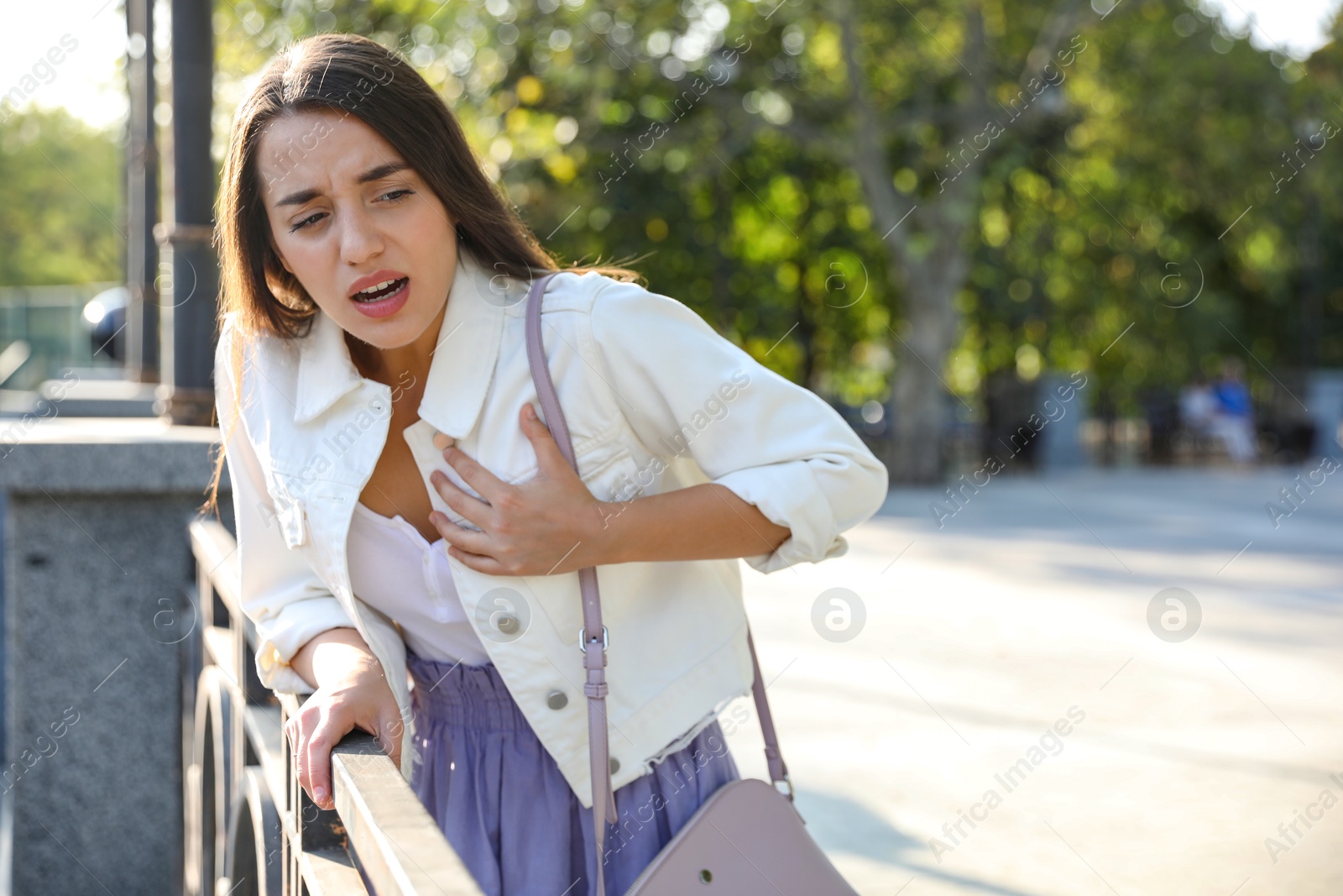 Photo of Young woman having heart attack on city street