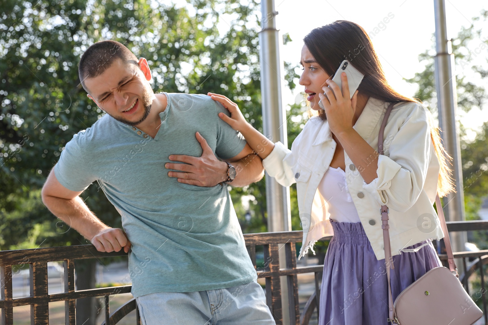 Photo of Woman calling ambulance to help man with heart attack on city street