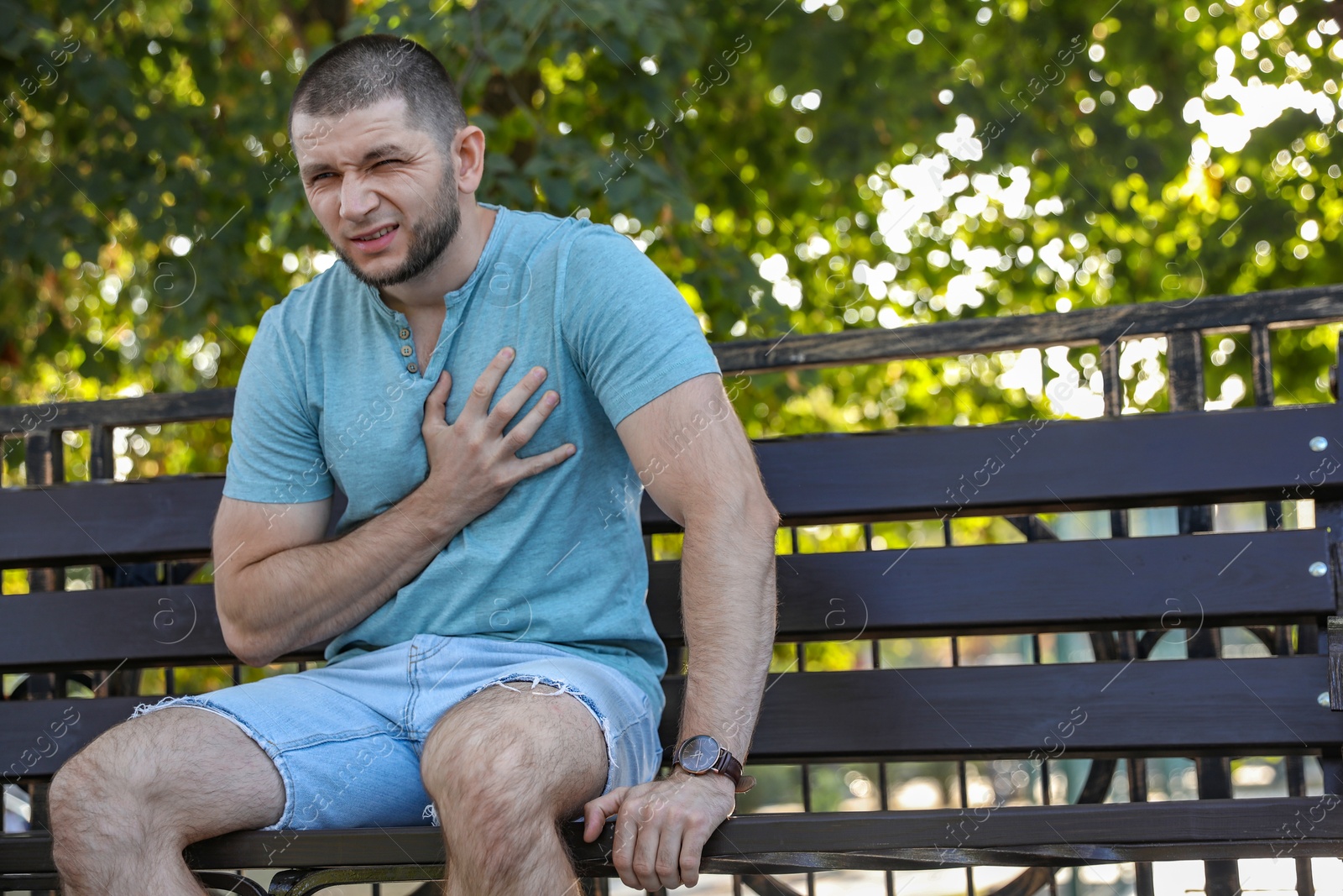 Photo of Man with heart attack sitting on bench in park