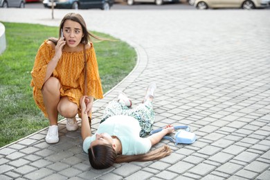 Photo of Woman calling ambulance to help unconscious person with heart attack on city street