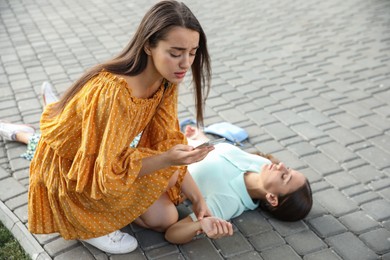 Photo of Woman checking pulse of unconscious person with heart attack on city street