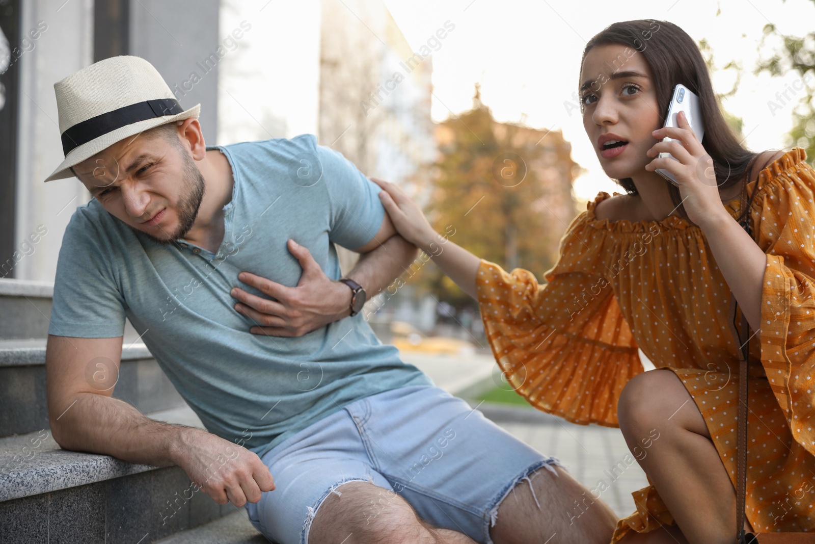 Photo of Woman calling ambulance to help man with heart attack on stairs