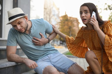 Photo of Woman calling ambulance to help man with heart attack on stairs