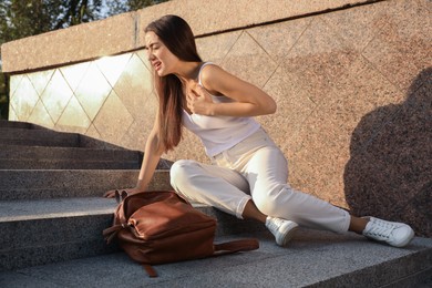 Photo of Young woman having heart attack on city street