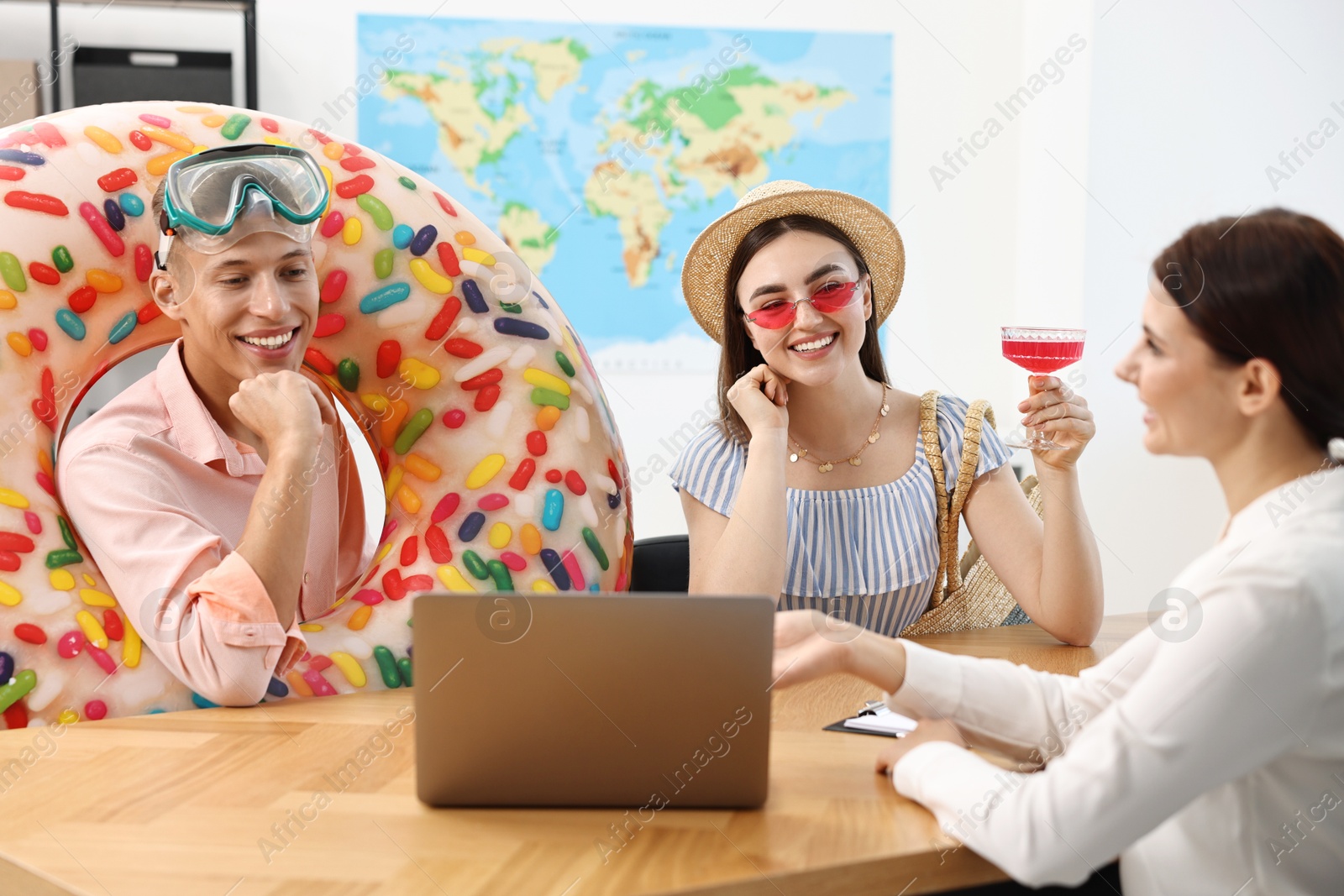 Photo of Happy couple planning vacation with travel agent at wooden table in office