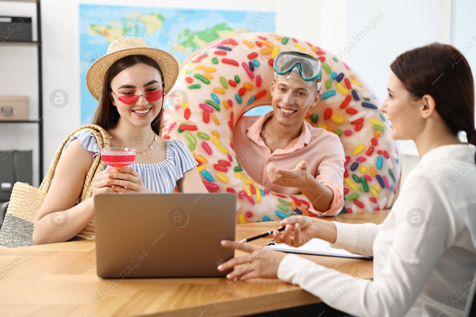 Photo of Happy couple planning vacation with travel agent at wooden table in office