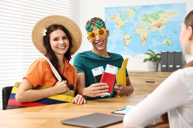 Photo of Happy couple planning vacation with travel agent at wooden table in office