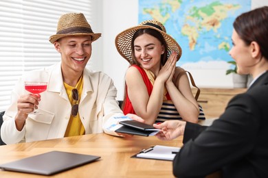 Photo of Happy couple planning vacation with travel agent at wooden table in office