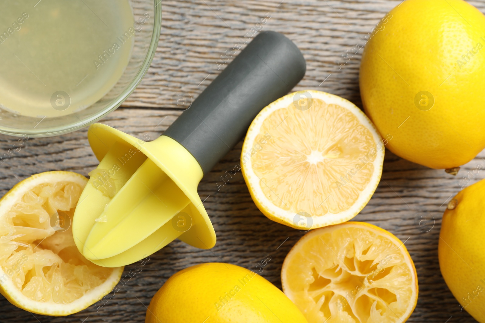 Photo of Plastic juicer and fresh lemons on grey wooden table, flat lay