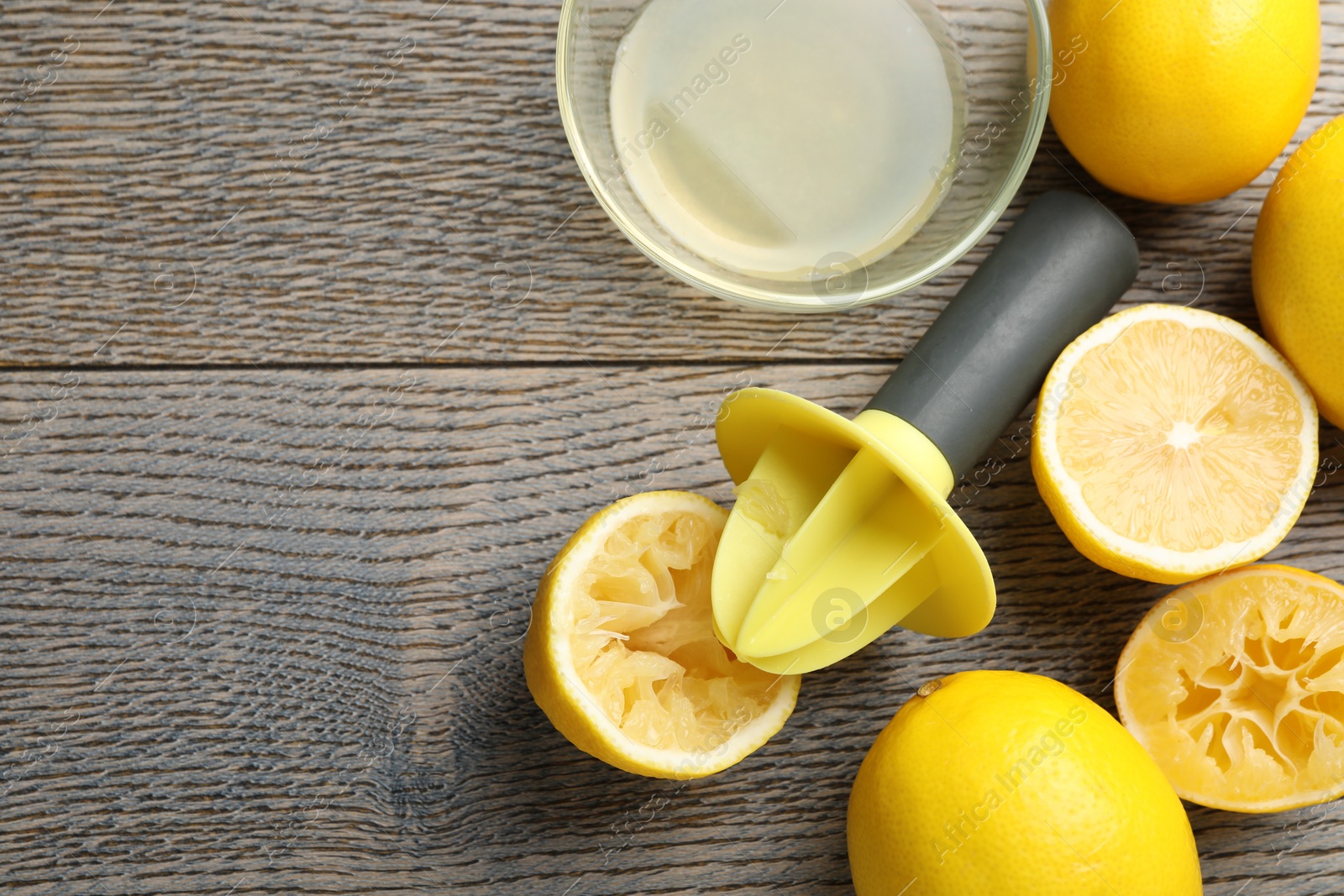 Photo of Plastic juicer and fresh lemons on grey wooden table, flat lay. Space for text