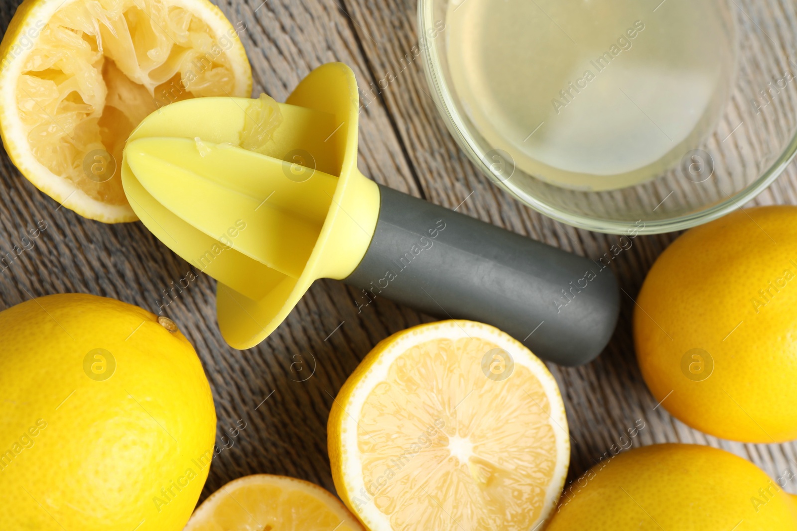 Photo of Plastic juicer and fresh lemons on grey wooden table, flat lay