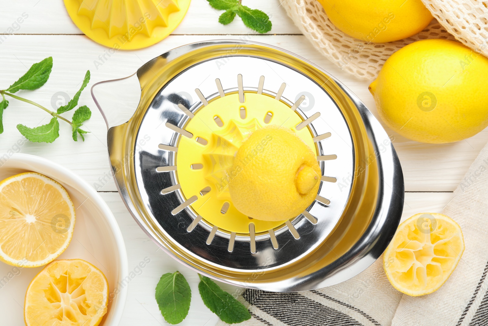 Photo of Plastic juicer and fresh lemons on white wooden table, flat lay