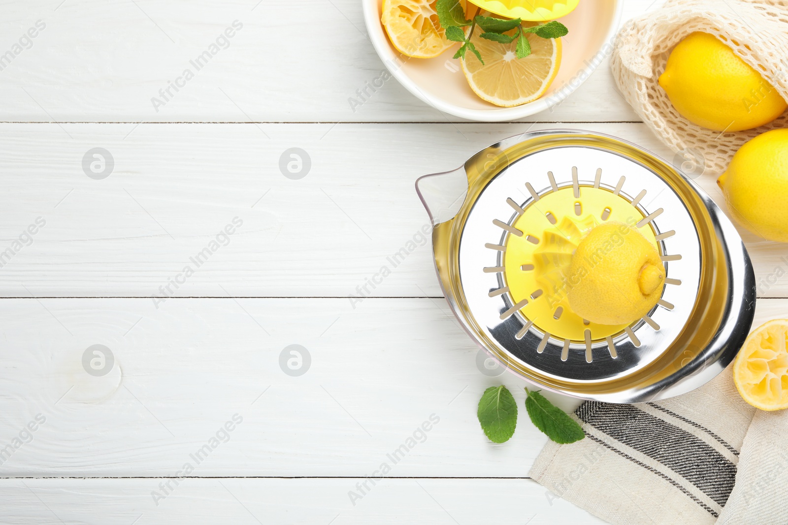 Photo of Plastic juicer and fresh lemons on white wooden table, flat lay. Space for text