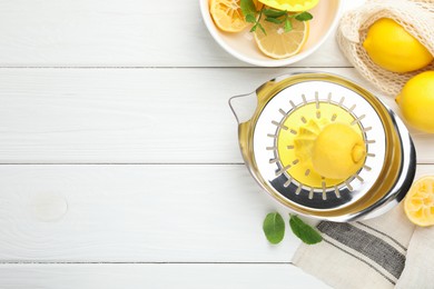 Photo of Plastic juicer and fresh lemons on white wooden table, flat lay. Space for text