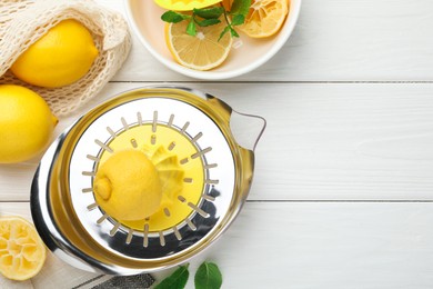 Photo of Plastic juicer and fresh lemons on white wooden table, flat lay. Space for text