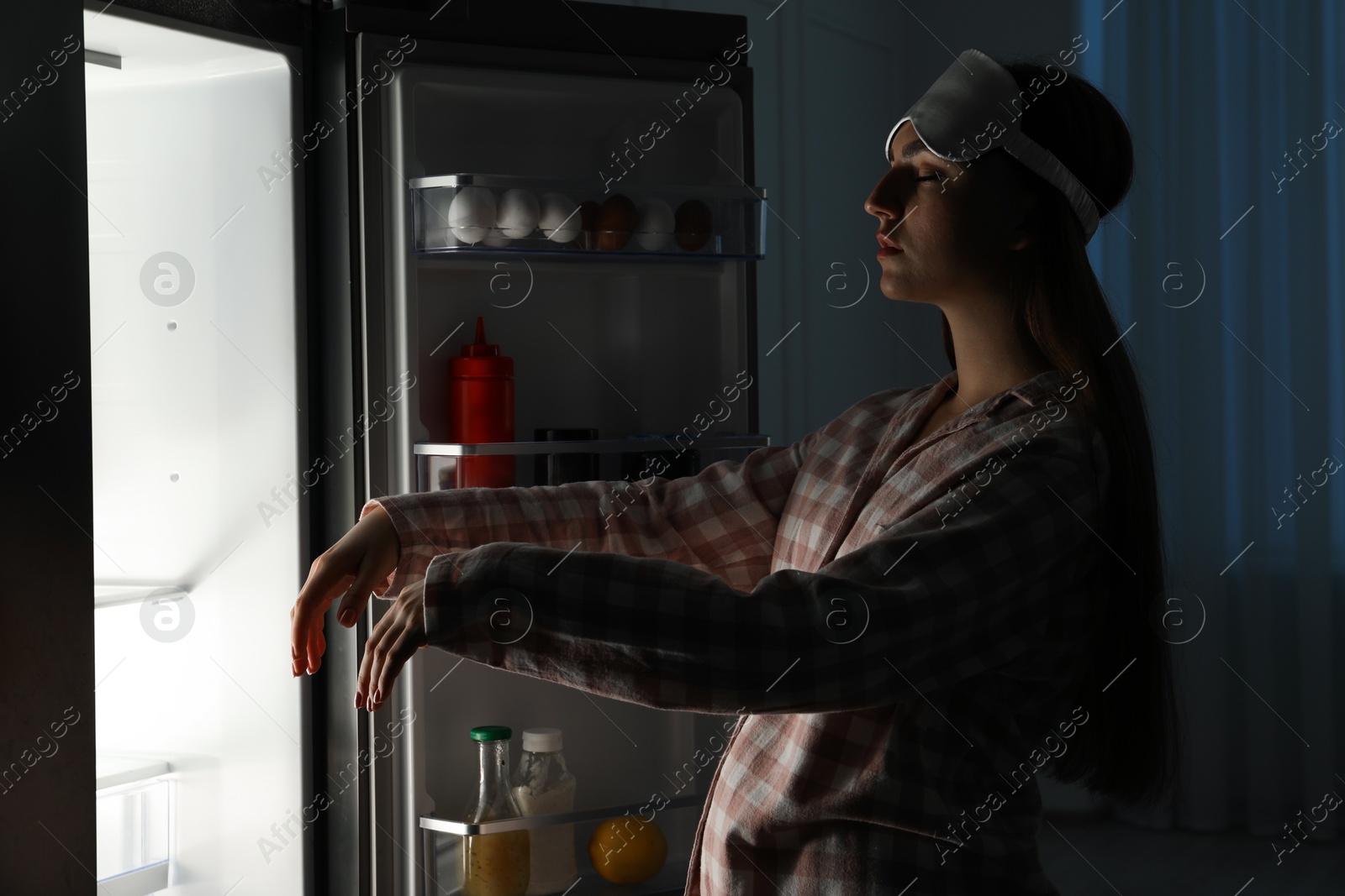 Photo of Young woman suffering from sleepwalking near fridge at home