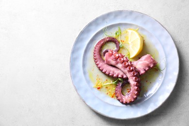 Photo of Appetizing octopus tentacles on light table, top view. Space for text