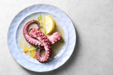 Photo of Appetizing octopus tentacles on light table, top view. Space for text