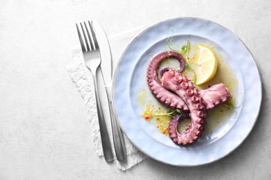 Photo of Appetizing octopus tentacles served on light table, top view