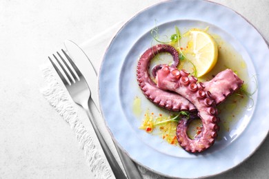 Photo of Appetizing octopus tentacles served on light table, top view