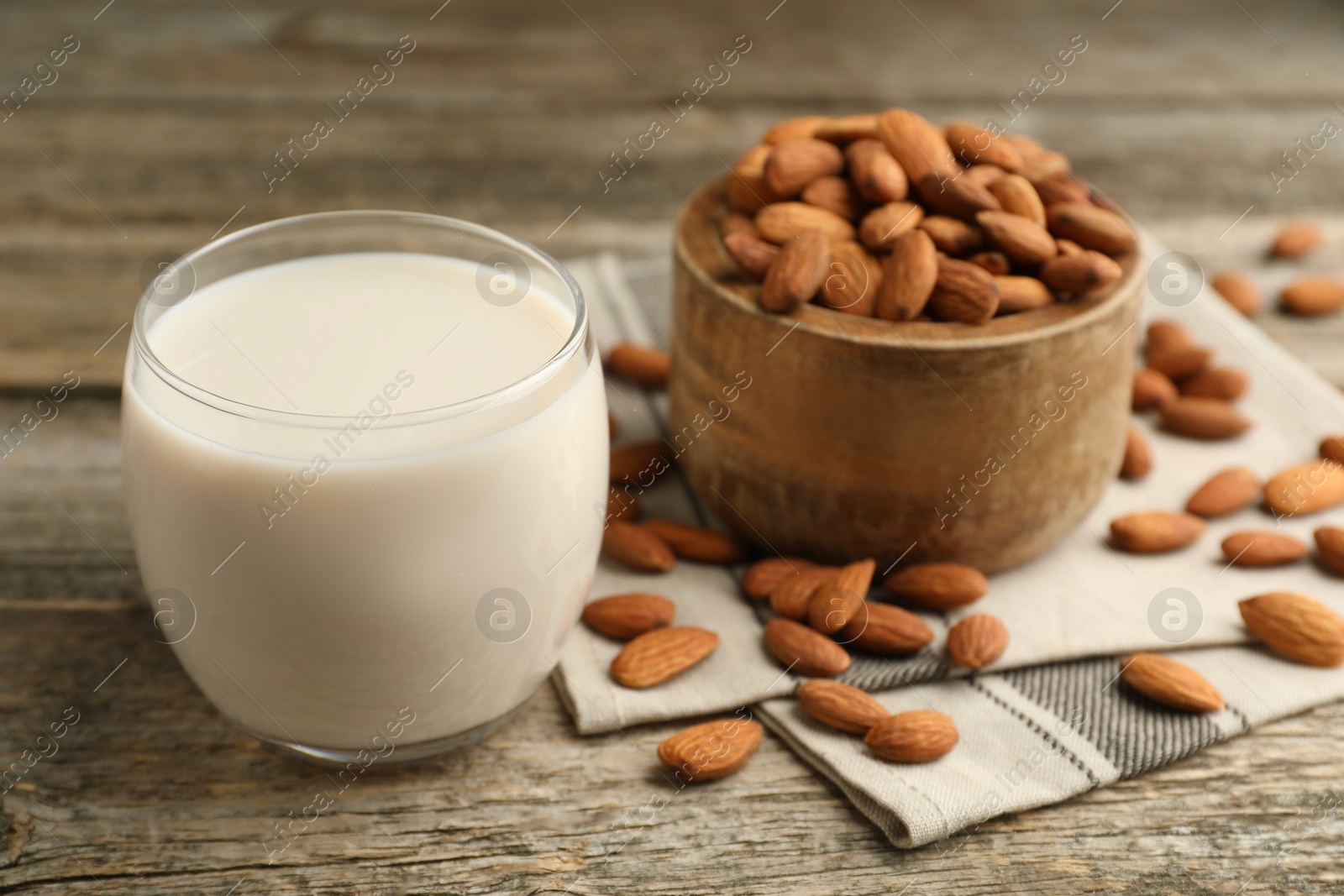 Photo of Fresh almond milk in glass and nuts on wooden table, closeup