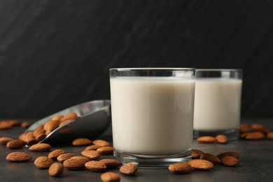 Photo of Fresh almond milk in glasses and nuts on dark grey table, closeup