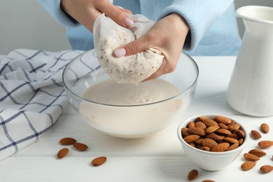 Photo of Woman making almond milk at white wooden table, closeup