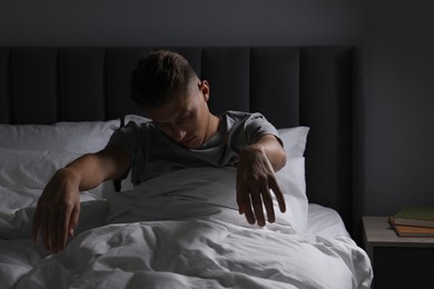 Photo of Young man suffering from sleepwalking on bed at home