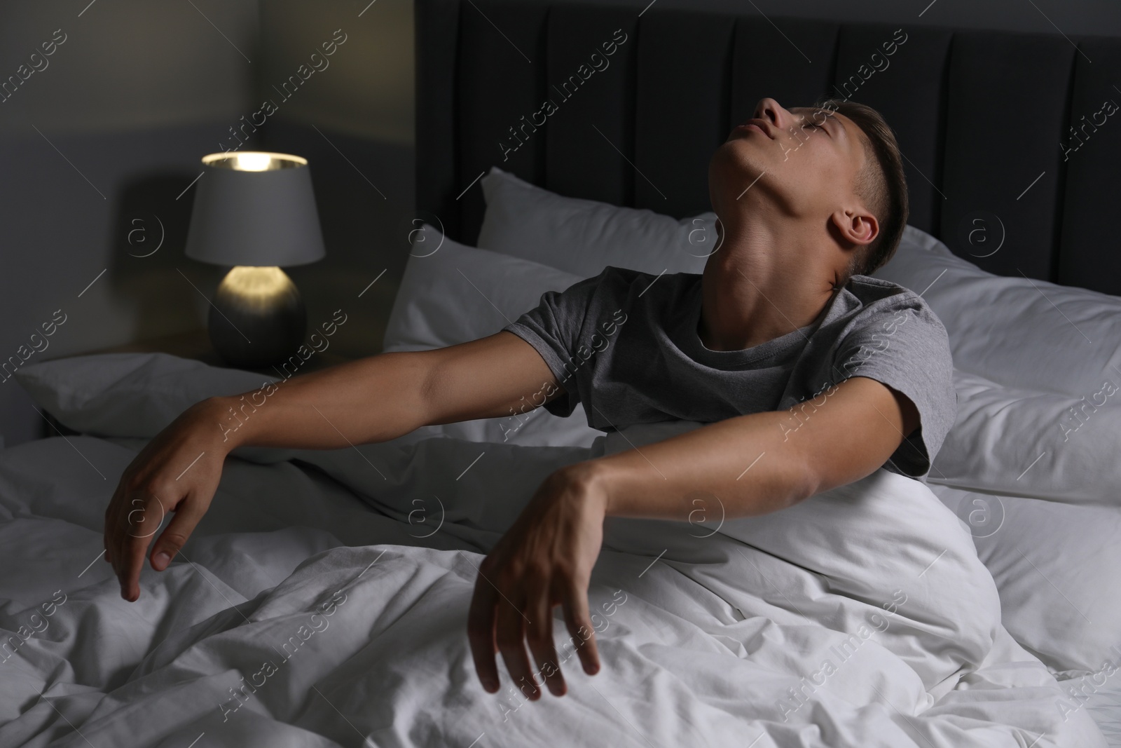 Photo of Young man suffering from sleepwalking on bed at home