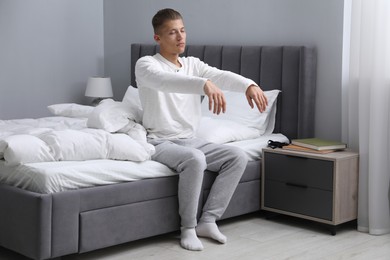 Young man suffering from sleepwalking on bed at home