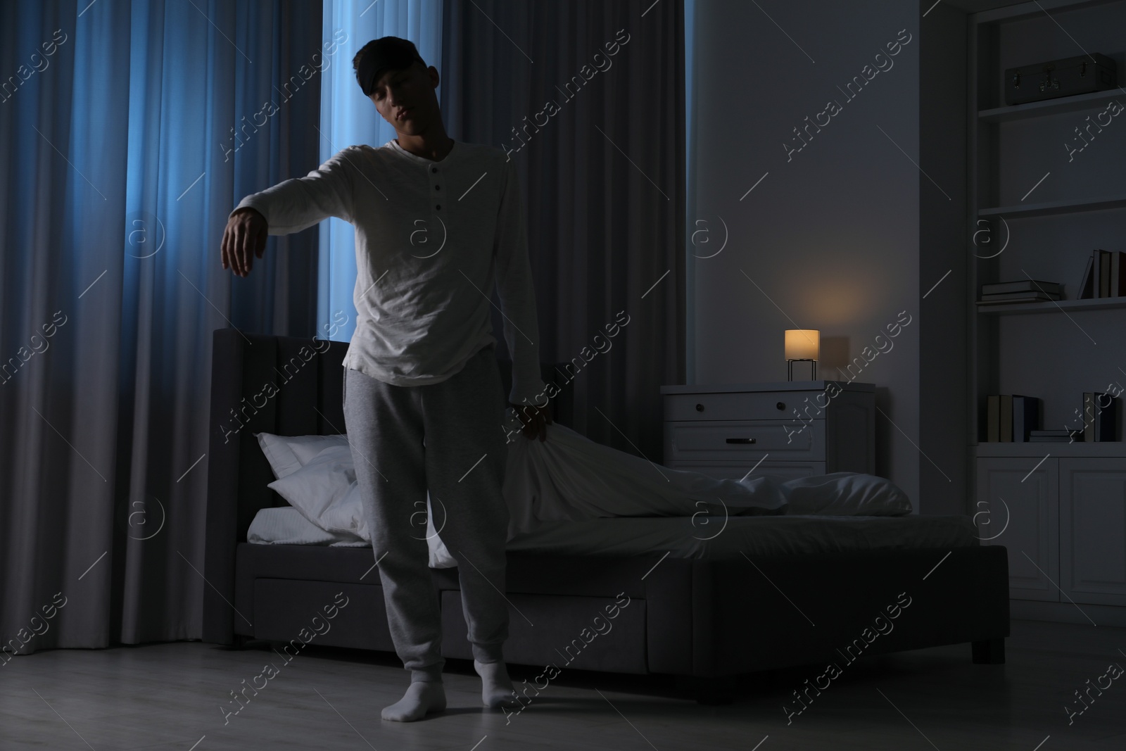 Photo of Young man suffering from sleepwalking at home, space for text