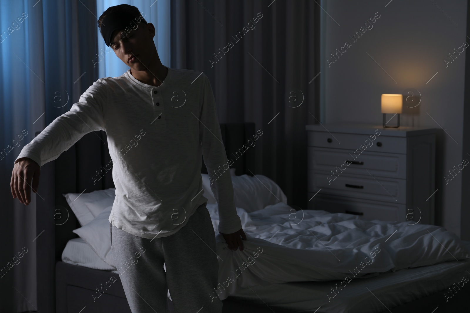 Photo of Young man suffering from sleepwalking at home, space for text