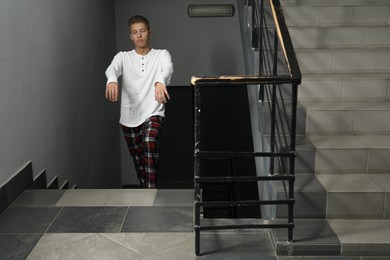 Photo of Young man suffering from sleepwalking on stairs indoors, space for text