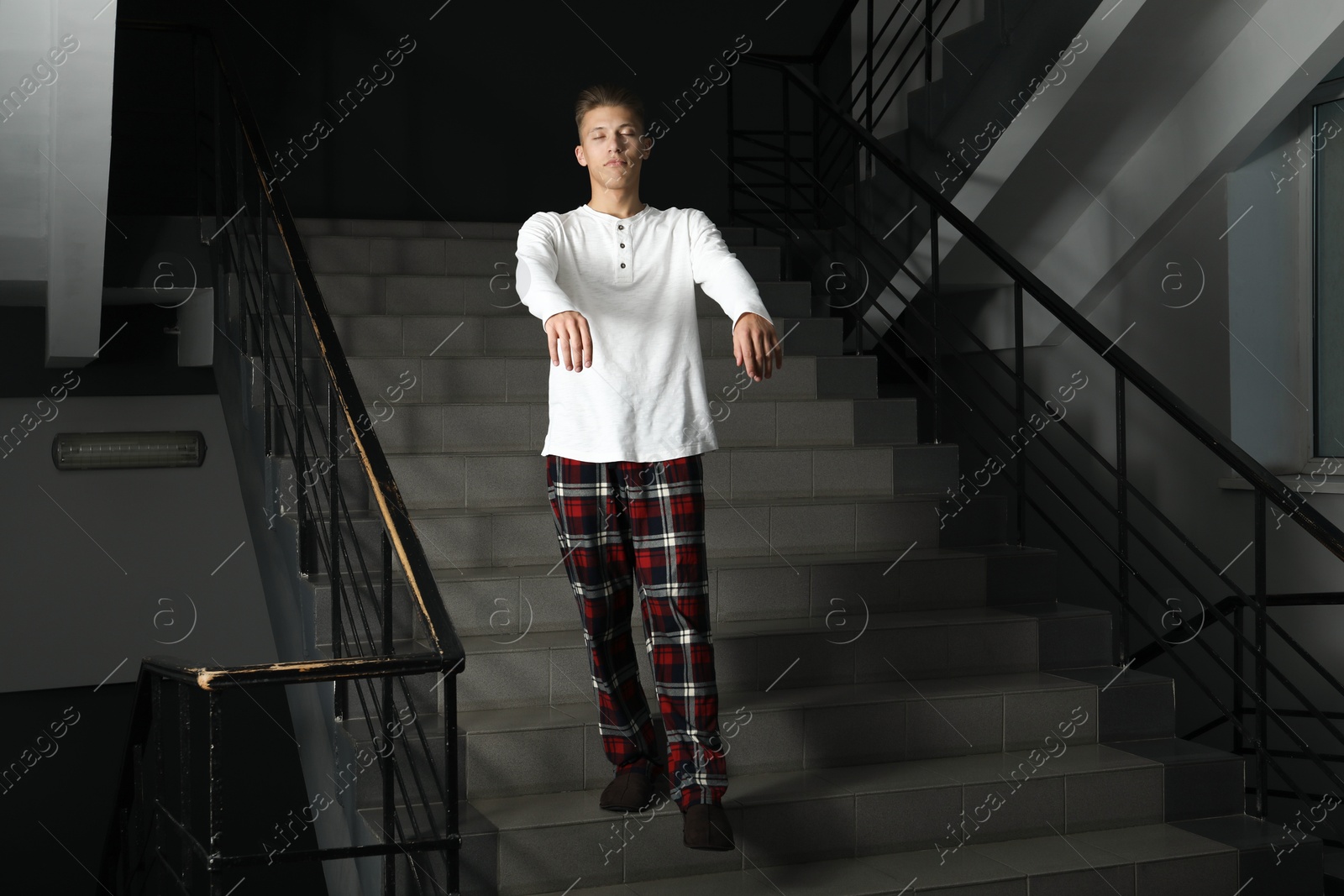 Photo of Young man suffering from sleepwalking on stairs indoors