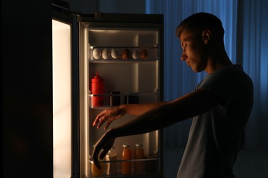 Young man suffering from sleepwalking near fridge at home