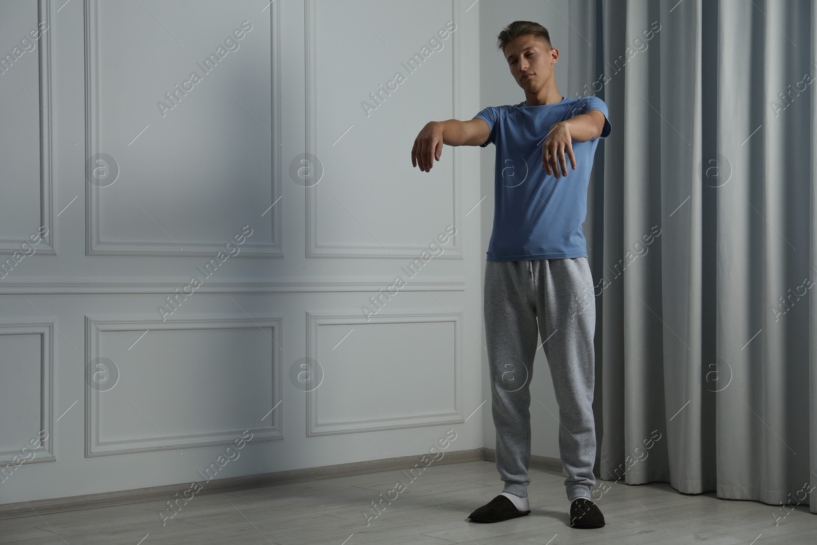 Photo of Young man suffering from sleepwalking at home, space for text