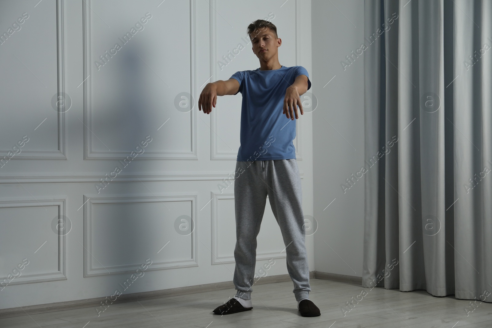 Photo of Young man suffering from sleepwalking at home, space for text