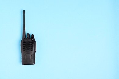 Photo of One walkie talkie on light blue background, top view. Space for text