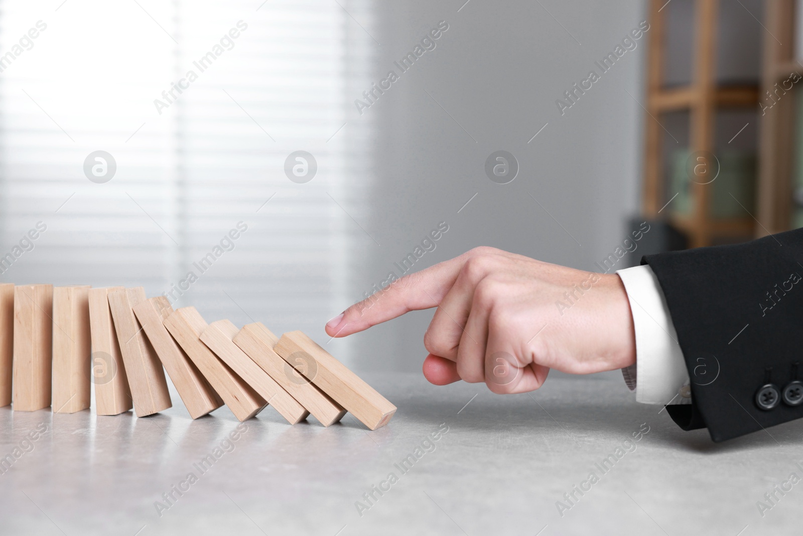 Photo of Domino effect. Man pushing wooden blocks at table, closeup